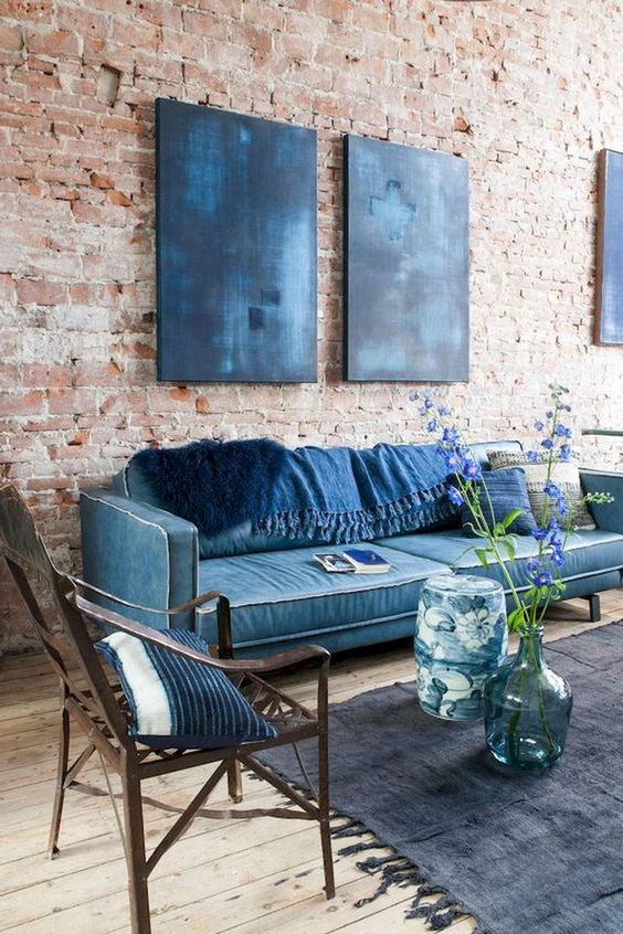navy furniture and pillows plus artworks contrast the red brick wall and a wooden floor