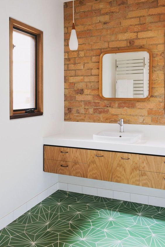 Red brick paired with green geometric tiles, a light colored vanity and a white countertop look chic and bold