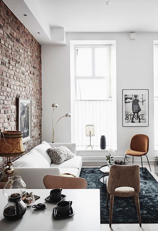 the exposed brick wall gives the living room a lot of character already, which is enhanced by the contrasting black and white