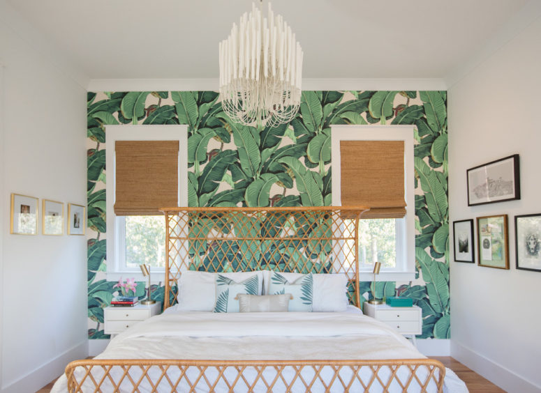 a tropical meets glam bedroom with wicker shades, a rattan bed, a glam chandelier and a statement tropical print wall  (Margaret Wright Photography)