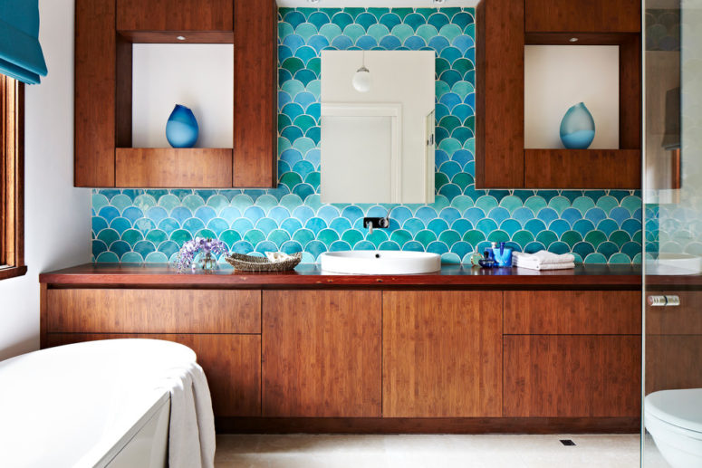 a beautiful sea-inspired bathroom with rich-stained wooden furniture, turquoise and blue fish scale tiles and an oval bathtub  (Camilla Molders Design)