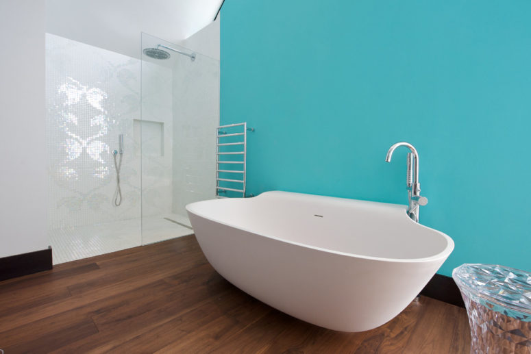 a minimalist ocean-inspired bathroom with a statement turquoise wall, a catchy-shaped tub and mosaic tiles in the shower  (Yorkshire Design Associates)
