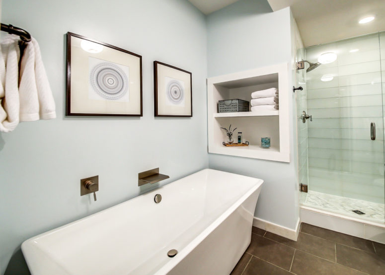 an aqua-colored bathroom with painted walls, matching tiles in the shower and beahcy artworks  (Karen Spiritoso Home Designs By Karen)