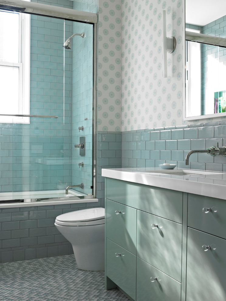 a sea-inspired bathroom with aqua and turquoise colored tiles and cabinets, printed wallpaper  (Rusk Renovations)