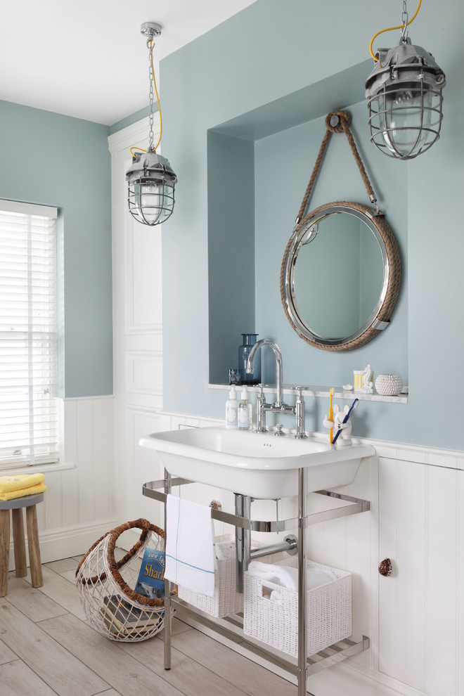 a nautical bathroom with a slate blue half wall, a vintage sink, vintage pendant lamps and a wooden floor  (Oliver Burns)