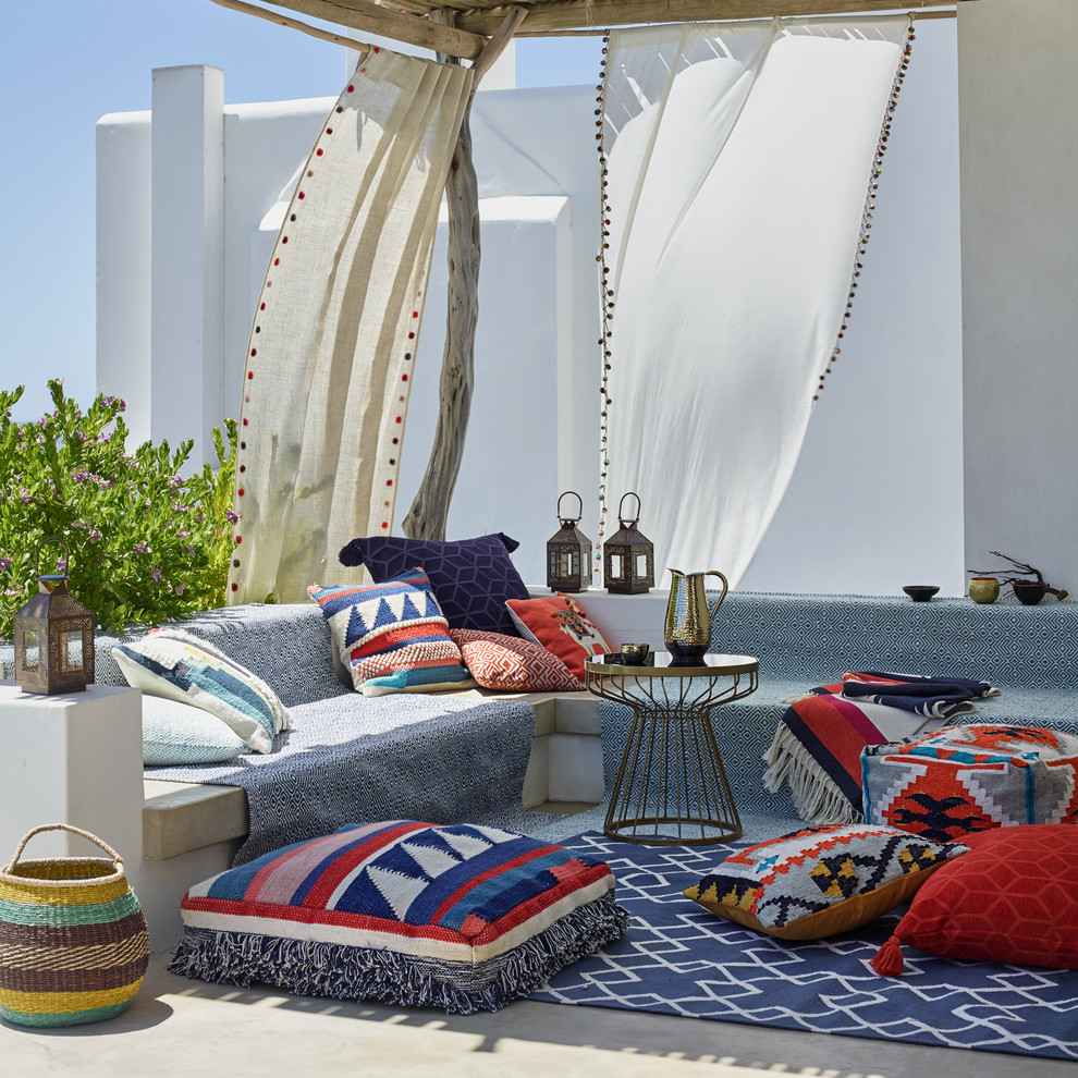 a bright Moroccan patio with a blue sofa, colorful printed pillows, Moroccan lanterns, baskets and airy curtains  (John Lewis & Partners)