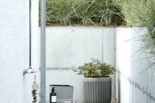 a Scandinavian outdoor shower with a concrete planter, stools and some accessories