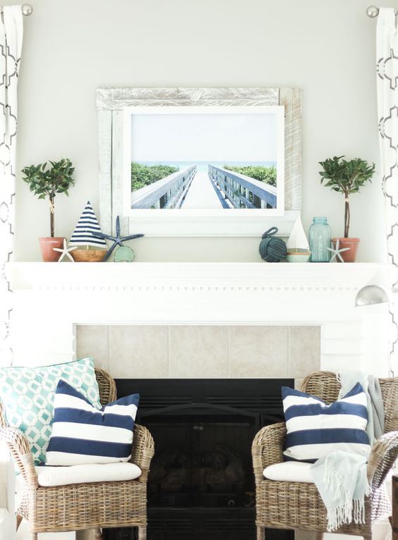 a beach mantel with mini boats, starfish, greenery in pots, a rope ball and a sea pier artwork