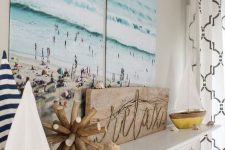 a beach mantel with seashells, two cute boats, a wooden sign and a gorgeous double beach artwork over it