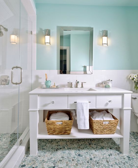 a beachy bathroom with a turquoise wall, a white vanity, baskets for storage for a welcoming space