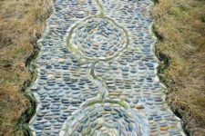 a bold pebble garden path with pebbles of various shades and with a catchy pattern plus curved borders