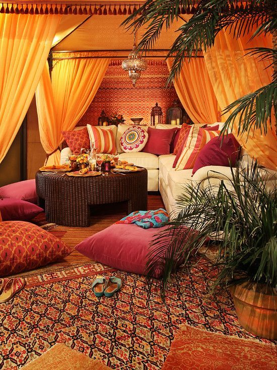 a bright Moroccan lounge with colorful pillows, a low wicker table, a Moroccan lantern with potted greenery