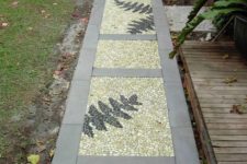 a catchy pebble garden path with neutral stone tiles, neutral pebbles and fern leaves done with black pebbles