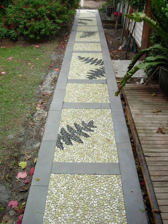 a catchy pebble garden path with neutral stone tiles, neutral pebbles and fern leaves done with black pebbles
