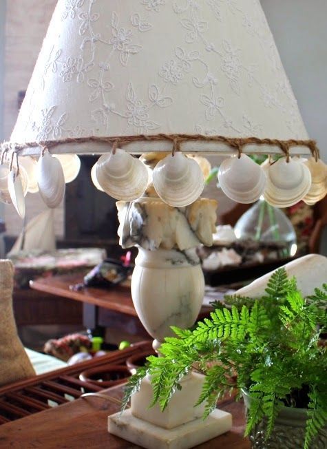 a catchy seaside table lamp of stone, with seashells hanging on the lampshade is a cool and bold idea