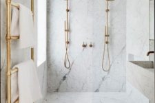 a chic and elegant bathroom done in white marble and gold hardware plus a floating sink and vanity