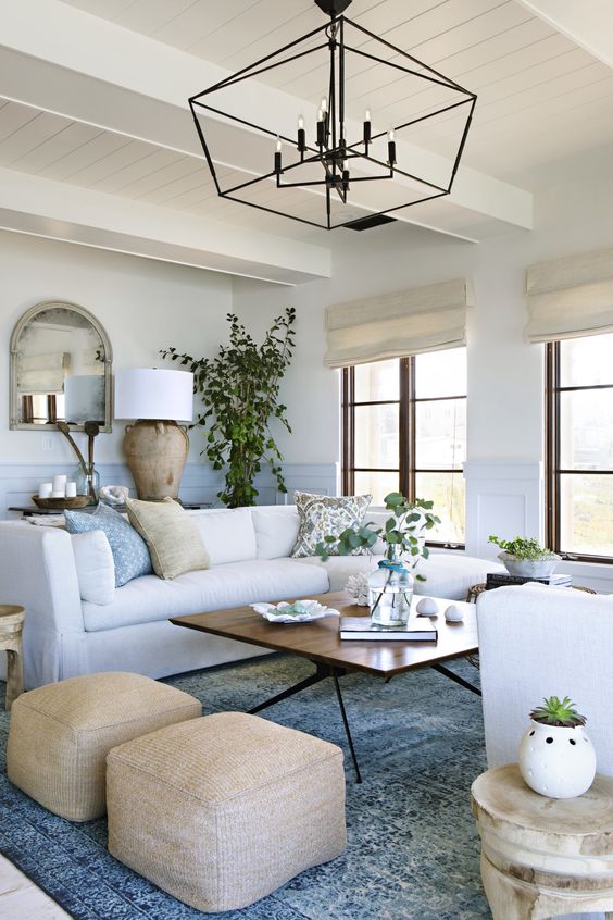 a chic coastal living room with touches of blue and light blue, creamy furniture and tan items plus a dirftwood lamp