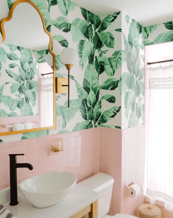 a chic tropical bathroom wiht tropical wallpaper, pink tiles, a bowl sink and touches of brass
