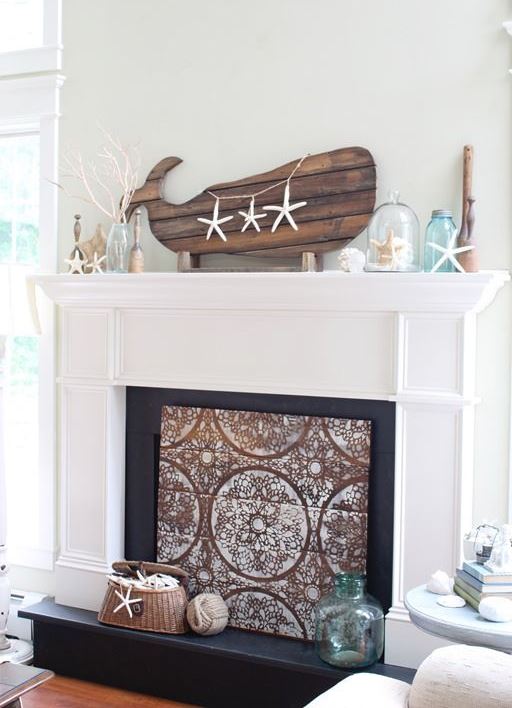 a coastal mantel with a wooden whale with starfish, starfish, bottles and jars with corals and seashells