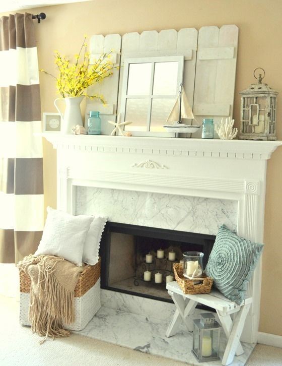 a coastal mantel with corals, starfish, seashells, a candle lantern, blue jars and blooming branches in a jug