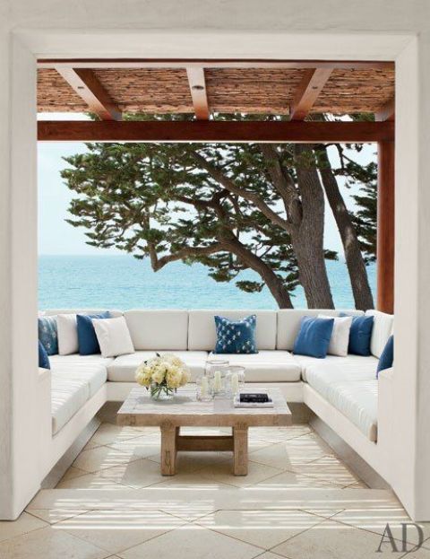 a contemporary seaside terrace with a U-shaped bench and blue and white pillows plus a gorgeous sea view