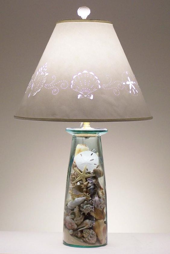 a cool table lamp with a glass base with seashells, starfish and beach sand inside and a printed lampshade for a beachy space