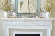 a fun beach mantel covered with net, some dried herbs in vases, corals, starfish, candles, birdies and a large boat in the center