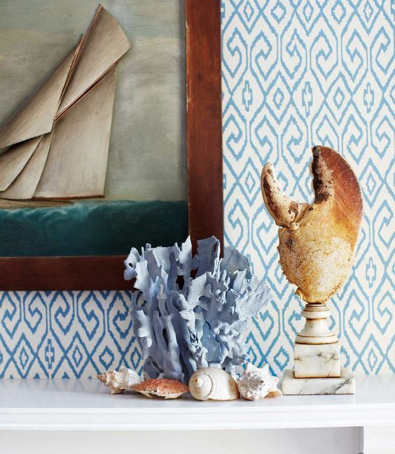 a lobster claw on a marble stand, a blue painted coral, seashells and a seaside artwork for a beachy mantel