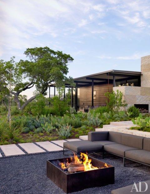a modern and chic outdoor space with a grey sectional and a metal box as a fire bowl is a lovely and cool space