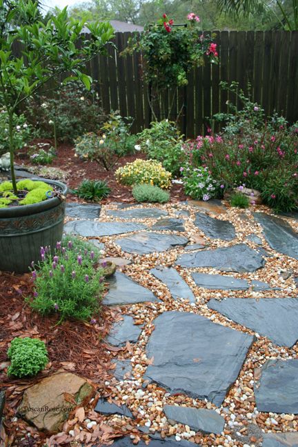 A relaxed and all natural garden path with pebbles and rough dark stones of various shapes and looks