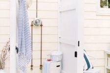 a seaside inspired outdoor shower with vintage white doors, wood and striped towels in blue