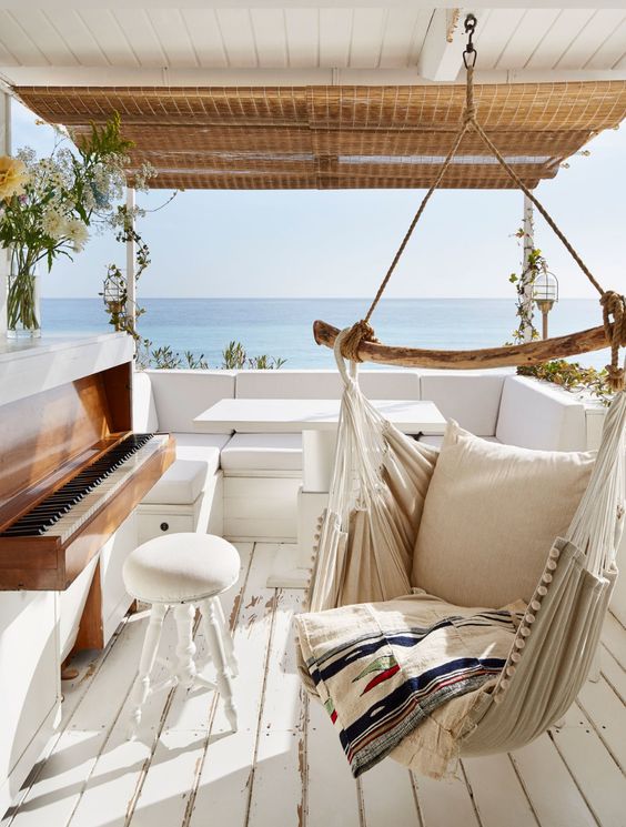 a seaside terrace with a wooden deck, a hanging chair, a sofa, a piano and a cool sea view is amazing