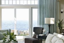 a stylish beahc living room with an aqua curtain, aqua furniture, a dark chair and a creamy sofa
