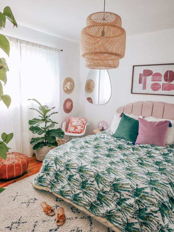 a tropical bedroom with tropical bedding, a wicker pendant lamp, potted plants and an abstract artwork