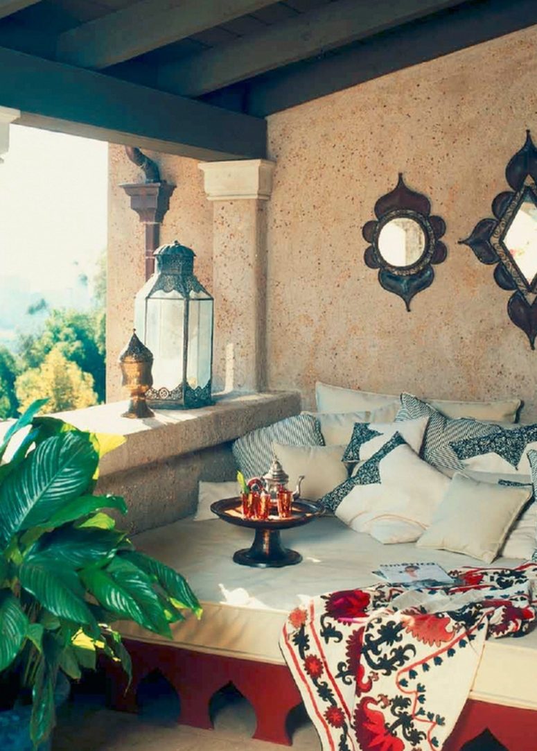 a welcoming Moroccan patio with a carved daybed, a vintage mirror, metal lanterns and a tray with drinks