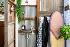 a welcoming outdoor shower with corrugated steel, weathered wood and a surf board