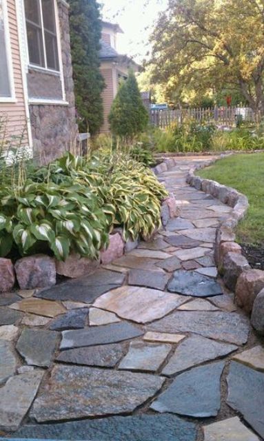 an elegant rough stone garden path with a high border looks stylish and very textural