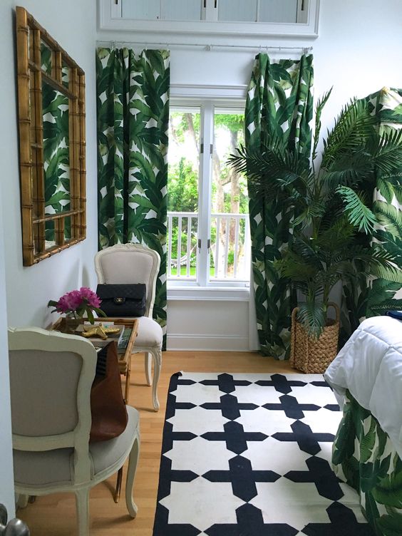 tropical print curtains and bedding, a potted palm, a bamboo mirror help to create an ambience in the bedroom