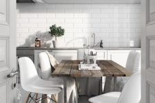 a Nordic kitchen with white cabinets and tiles, a rough wooden table, modern white chais and a geometric chandelier