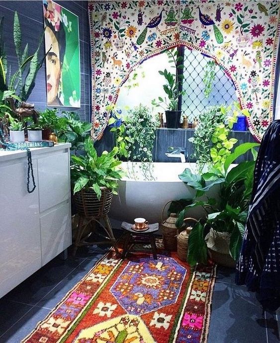 a boho Moroccan bathroom with a colorful curtain, a brugth rug and artwork and lots of potted greenery