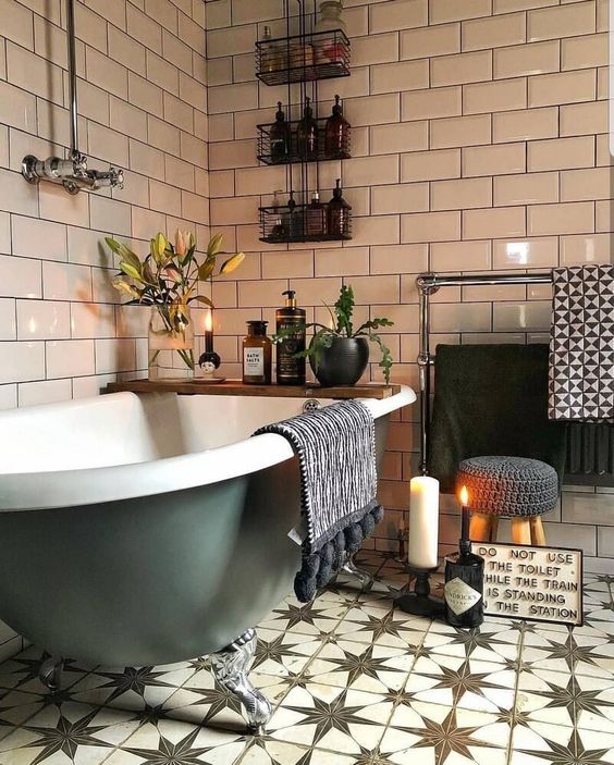 a boho bathroom done with pretty Moroccan tiles, potted plants and blooms, candles and a green clawfoot tub