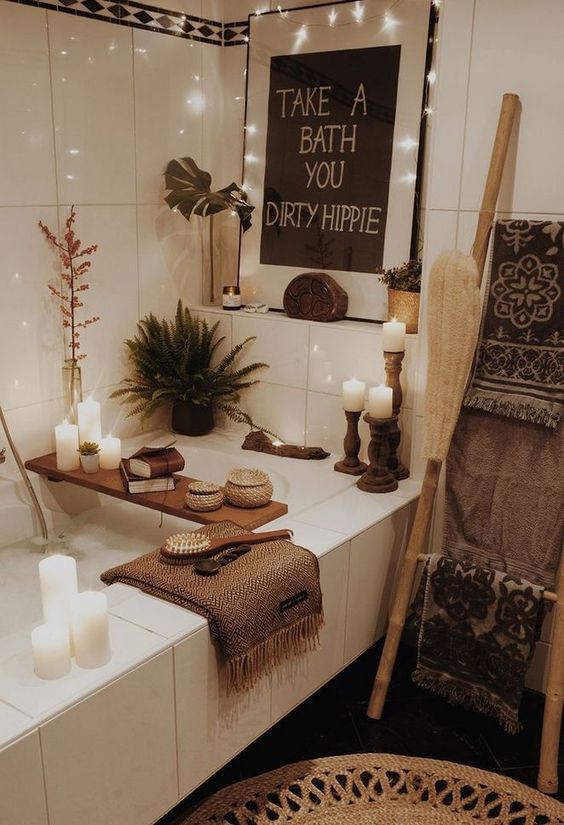 a boho bathroom with lights, an artwork, a wooden caddy, lots of candles and jute touches