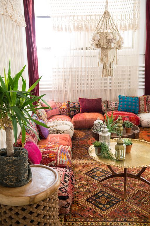 a boho living space with floor cushions and pillows instead of a sofa, rugs and pendant lamps