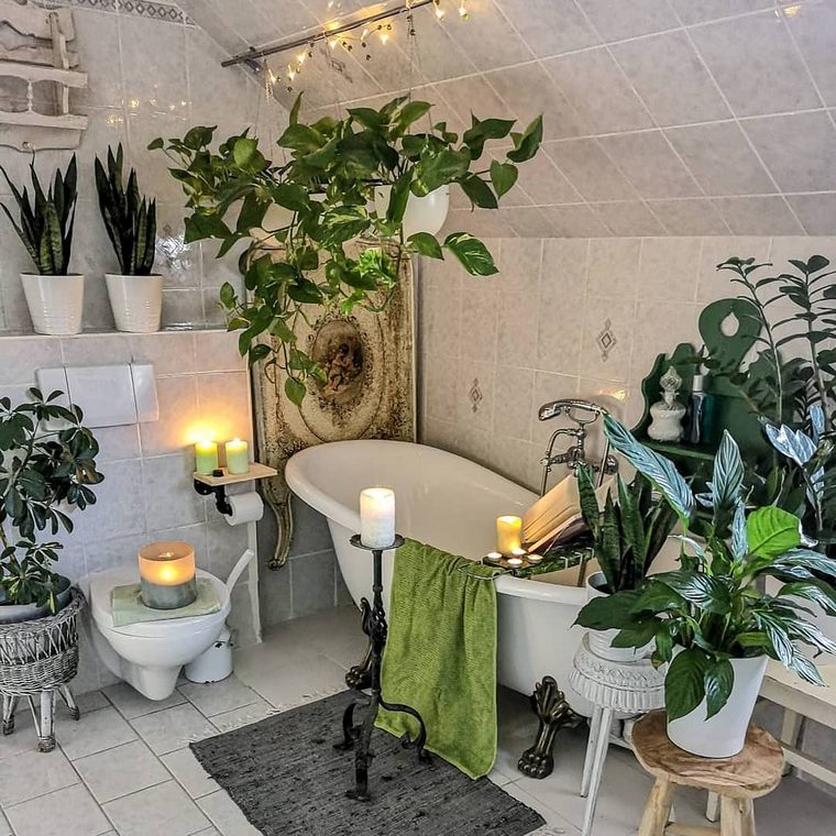 a boho oasis with lots of potted greenery, candles, lights and a clawfoot bathtub plus baskets