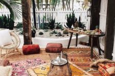 a boho patio with colorful printed rugs, cushions, ottomans, rattan and wooden furniture, Moroccan lanterns