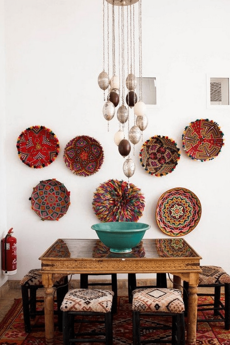 a bold Moroccan dining zone with a carved wooden table, printed stools, decorative plates on the wall and pendant lamps hanging on chains