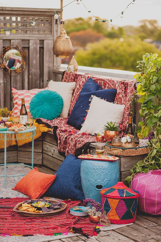 a bright boho patio with colorful textiles, rugs, pillows, Moroccan lanterns, woven baskets and colorful side tables