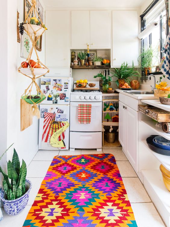 a bright kitchen with colorful textiles, a macrame fruit holder and lots of potted greenery