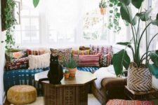 a chic Moroccan living room with bright patterned textiles, a painted coffee table and potted greenery