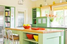 a chic farmhouse mint kitchen with light yellow walls, mint green cabinets, wood and stone countertops and yellow touches